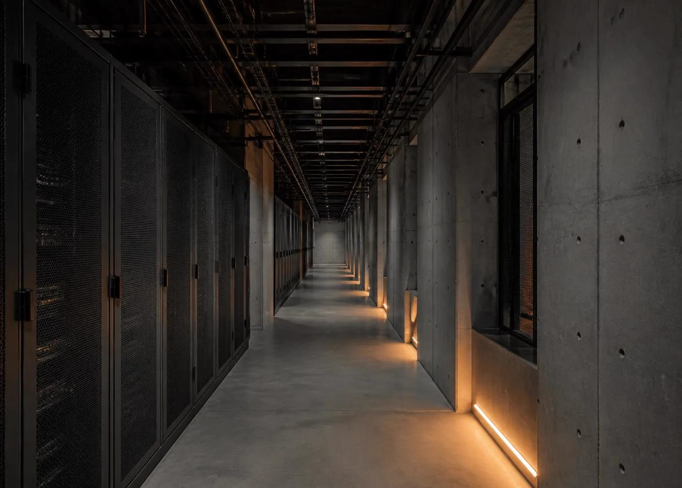 Row of server cabinets in a data centre corridor with low-level amber lighting